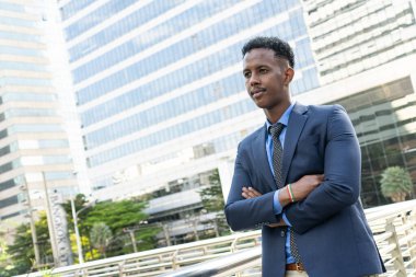 Şehirdeki iş adamları. Yakışıklı bir iş adamının portresi. Modern iş adamı. Kendine güvenen, takım elbiseli ve gözlüklü genç bir adam arka planda şehir manzarasıyla dışarıda dikilirken.