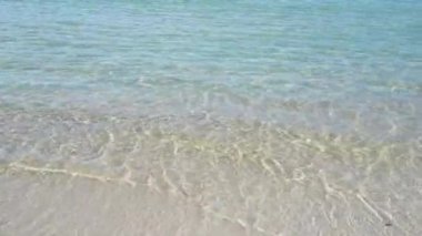 Sahildeki deniz kumu manzarası. Turkuvaz deniz dalgaları kumlu kıyı şeridinde kırılıyor. 