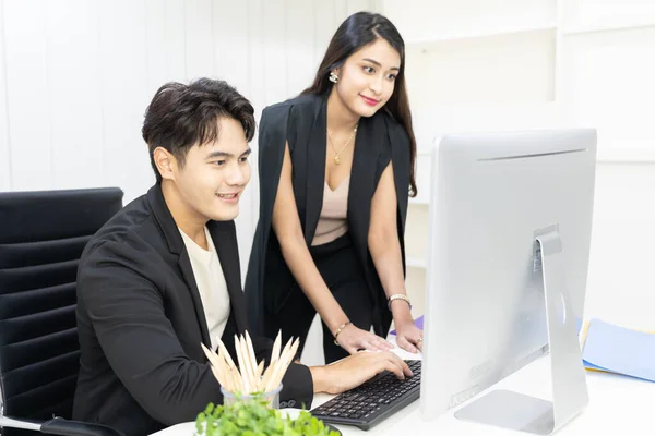 President and secretary using computer to working and  discuss together at office. businessman and businesswoman talking and looking computer in the office.