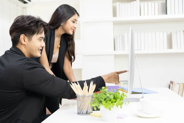 President and secretary using computer to working and  discuss together at office. businessman and businesswoman talking and looking computer in the office.