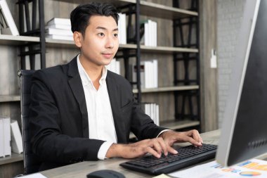 Portrait of business man using computer at workplace in an office. positive business man smiling looking into screen of computer.