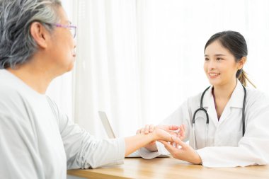 Doktor yaşlı hastasının nabzını kontrol ediyor..