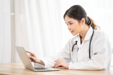 Asyalı kadın doktor bilgisayarlı bilgisayarla hastayla uzaktan konuşma videosu kullanıyor. Tıbbi pratisyen hekimin hastane ofisindeki hastaya sanal konsültasyon yapması.