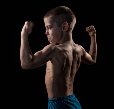  Siyah arka planda kaslı genç bir çocuk. Karanlık stüdyo çekimi