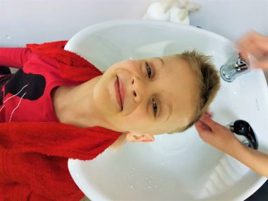 Çocuk berber dükkanında saçını yıkatıyor.