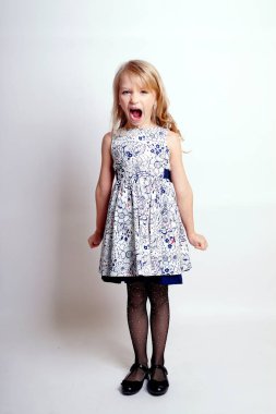 Gri elbiseli güzel bir kız çocuğu. Issız bir stüdyo fotoğrafı.