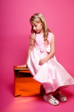Pembe elbiseli güzel bir kız çocuğu. Issız bir stüdyo fotoğrafı.