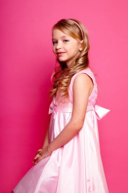 Pembe elbiseli güzel bir kız çocuğu. Issız bir stüdyo fotoğrafı.