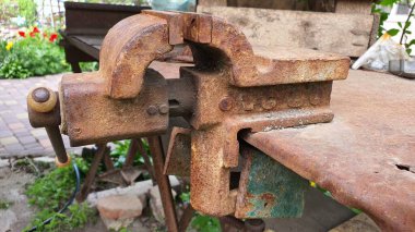 Paslı bir mengene paslı metal bir levha ile kaplı bir masaya vidalanır.