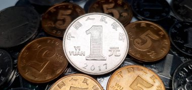 Birkaç sarı 5-jiao bozukluğunun üzerinde yatan bir Çin Yuan 'ının yakın plan çekimi. Arka planda bir sürü Çin Yuan sikkesi var. 2017 'de bir yuan madeni para basıldı.