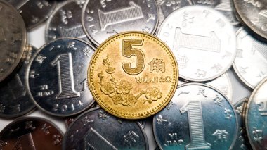 Beş Çin jiao sikkesi yakın çekim. Arka planda bir Çin Yuan 'ına ait bir sürü bozuk para var.