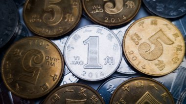 5 jiao parasıyla çevrili 1 Çin Yuan sikkesi. Arka planda bir Çin Yuan 'ına ait bir sürü bozuk para var.