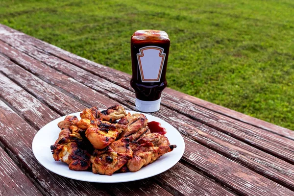 Grilled barbecue on table with barbecue sauce and green grass background