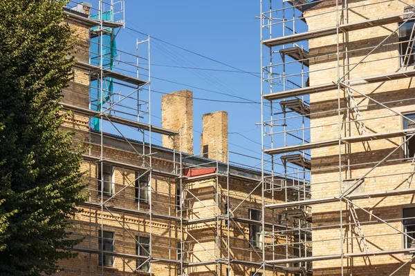 Ett Brunt Tegelhus Med Metallhyllor Och Ett Mörkgrönt Träd Bredvid — Stockfoto