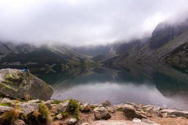 Polonyalı Tatra dağlarının göldeki yansımaları ve inanılmaz beyaz bulutların olduğu sihirli bir manzara.