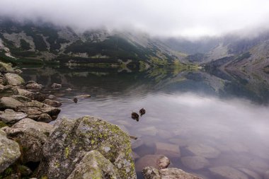 Polonyalı Tatra dağlarının göldeki yansımaları ve inanılmaz beyaz bulutların olduğu sihirli bir manzara.