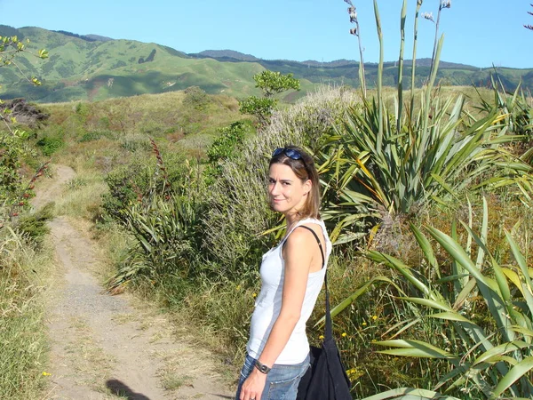 A young woman takes a walk along the wild Kapiti Coast on a sunny day in New Zealand.