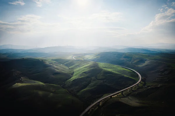 Bu, dolambaçlı yolu olan tipik ve güzel bir İtalyan manzarasının fotoğrafı. Güneş yavaşça batıyor, İtalyan tepelerinde güzel bir ışık oyunu yaratıyor.. 