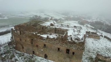 Terk edilmiş, bakımsız bir manastırın hava görüntüsü. Dışarıda kar yağıyor. Adı Convento dei Frati Cappuccini ve 16. yüzyıldan kalma. Grottole, Güney İtalya 'da yer almaktadır..