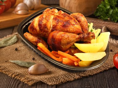 Kızarmış tavuk budu, sebze ve baharatla ahşap arka planda.