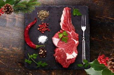 Baharatlı çiğ biftek ve ahşap masada otlar.