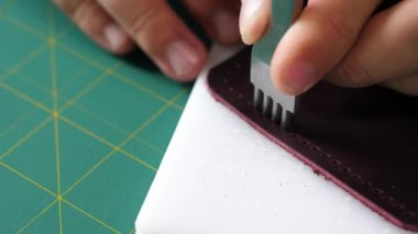 Adam deriyi yumruklarla delip iplik dikmek için delik açıyor. Çerçeveyi kapatıyoruz. Piercere yakın, deri içeceğiyle solmuş..