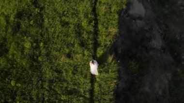 Beyaz elbiseli bir kız sahada koşuyor. Sahadaki bir kızın havadan çekilmiş fotoğrafı. Havadan bir düğün atışı. Gökyüzünün altında bir İHA 'dan çekiliyor, kumlu arka plan.