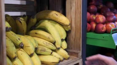 Muzlar mağazanın rafında. Muzlu tezgah. Taze doğal muz. Kız muz alıyor. Yakın plan..