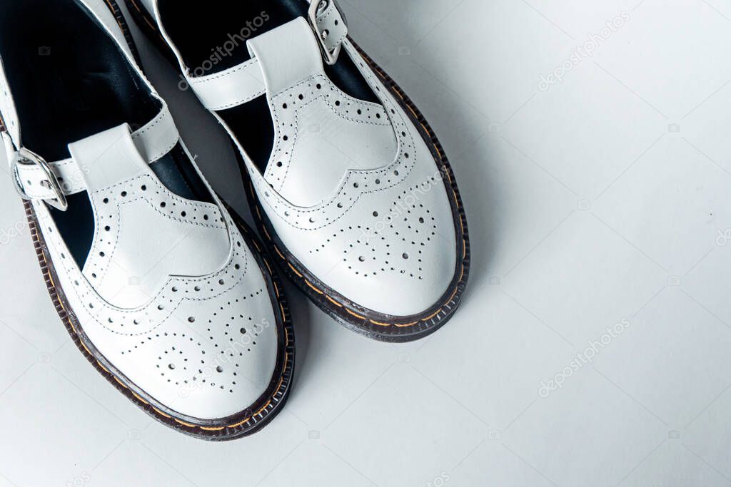 White mary jane shoes with wingtip pattern and rubber sole on a white background