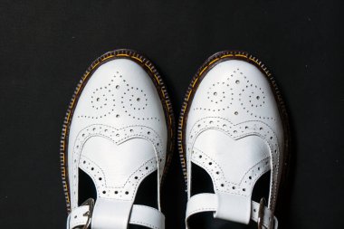 White mary jane shoes made of genuine leather with accurate pattern details on a black background clipart