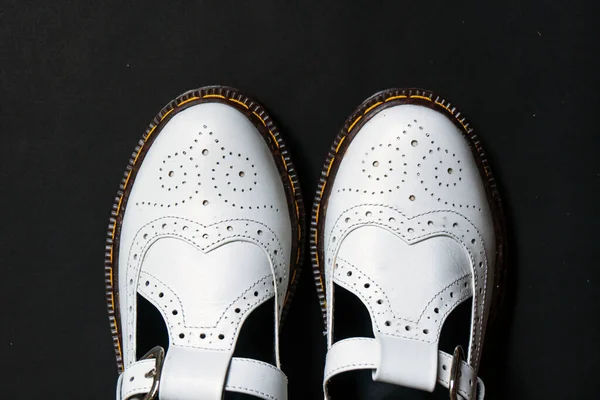 黒の背景に正確なパターンの詳細を持つ本革で作られた白いメアリージェーンの靴 ストックフォト
