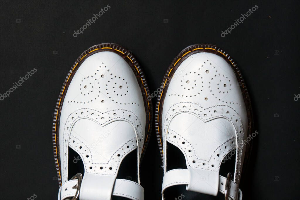 White mary jane shoes made of genuine leather with accurate pattern details on a black background
