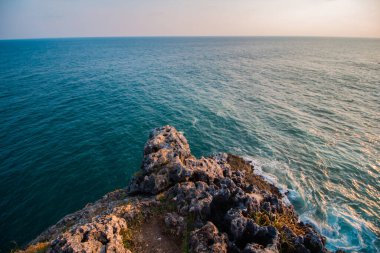 when the sun goes down in the middle of the ocean coupled with the beauty of the cliffs with corals scattered everywhere with big waves characterizing the beach in Gunung Kidul, Indonesia
