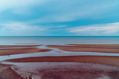 Talisayan, Doğu Kalimantan 'daki kara kum plajı geri çekiliyor, dalgalar nispeten sakin ve gökyüzü bulutlu.