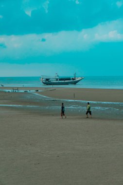 Talisayan, Doğu Kalimantan 'daki kara kum plajı geri çekiliyor, dalgalar nispeten sakin ve gökyüzü bulutlu.