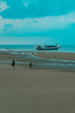 Talisayan, Doğu Kalimantan 'daki kara kum plajı geri çekiliyor, dalgalar nispeten sakin ve gökyüzü bulutlu.