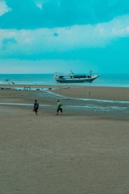 Talisayan, Doğu Kalimantan 'daki kara kum plajı geri çekiliyor, dalgalar nispeten sakin ve gökyüzü bulutlu.