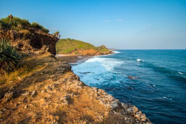 Okyanusun ortasında güneş battığında, Endonezya, Gunung Kidul 'daki sahili karakterize eden büyük dalgalarla her yere dağılmış mercanlar ve uçurumların güzelliği ile birleşir.