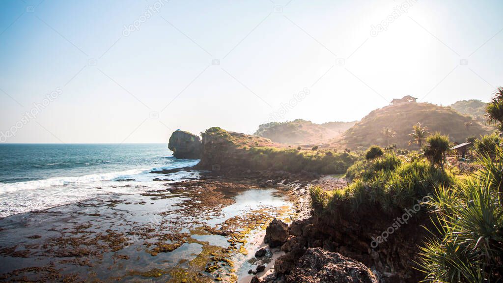 when the sun goes down in the middle of the ocean coupled with the beauty of the cliffs with corals scattered everywhere with big waves characterizing the beach in Gunung Kidul, Indonesia