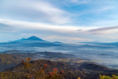 Menoreh tepelerinden, Kulon Progo 'dan, Endonezya' dan Suroloyo 'nun tepesinden güzel bir altın gün doğumu. Güneş tepenin arkasından doğuyor. Böylece Merapi Dağı, Merbabu, Sindoro ve Sumbing' i görebilirsiniz.