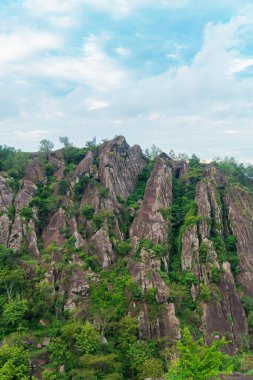 An amazing ancient stone hill that has existed hundreds of millions of years ago, this hill is dominated by ancient stone with green trees, which are still natural and beautiful, with views of rice fields in front and bright blue sky behind