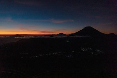 The peak of Sikunir, Dieng is a spot to watch the stunning Golden Sunrise with a golden yellow sky with a sea of clouds, also visible majestic hills around it and Mount Sindoro, Prau and Sumbing right in front of it.