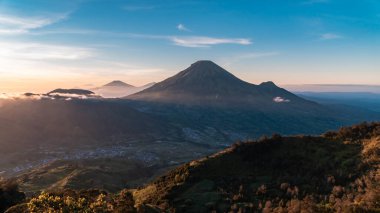 The peak of Sikunir, Dieng is a spot to watch the stunning Golden Sunrise with a golden yellow sky with a sea of clouds, also visible majestic hills around it and Mount Sindoro, Prau and Sumbing right in front of it.