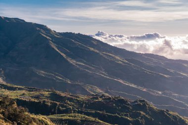 The peak of Sikunir, Dieng is a spot to watch the stunning Golden Sunrise with a golden yellow sky with a sea of clouds, also visible majestic hills around it and Mount Sindoro, Prau and Sumbing right in front of it.