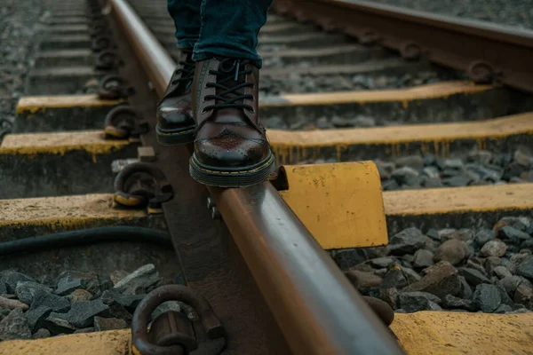 Close up of a dark brown 8-hole wingtip brogue boot when worn for a walk on the railroad track when the evening sky was dark and cloudy