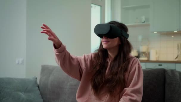 Девушка сидит в очках виртуальной реальности и листает в социальных сетях — стоковое видео