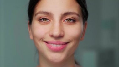 Kız kameraya başını eğerek gülümsüyor. Bir kadının yakın plan portresi