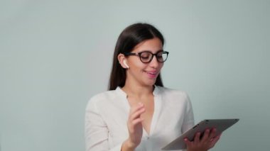 Kız iş yerinde kulaklıkla elinde tabletle iletişim kuruyor. Kız çağrıya kulaklıkla cevap veriyor. Ofiste çalışan kız.