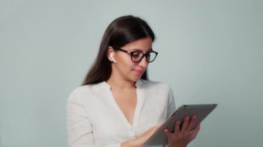 Kız ofiste kulaklıklı bir tabletle çalışıyor. Kız tablete bir şey yazıyor. Çalışma ortamı
