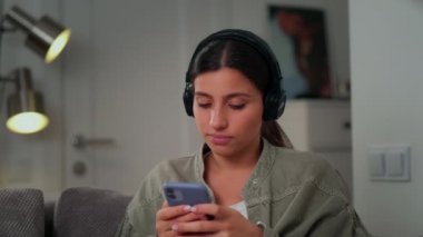 Kulaklıklı bir kız telefondaki bir banka kartının detaylarını dolduruyor. Kart detaylarını telefondaki programa girin. Banka kartı, kulaklık, telefon, orta plan